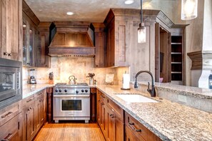 A kitchen with wooden cabinets, a stainless steel stove, granite countertops, and a built-in sink. - KBM Resorts | Luxurious Vintage on the Strand | Ski Access, 2 Family rooms, 3 Fireplaces, Free Shuttle to Lifts! Pri Hot tubVIN-17 (Park City)