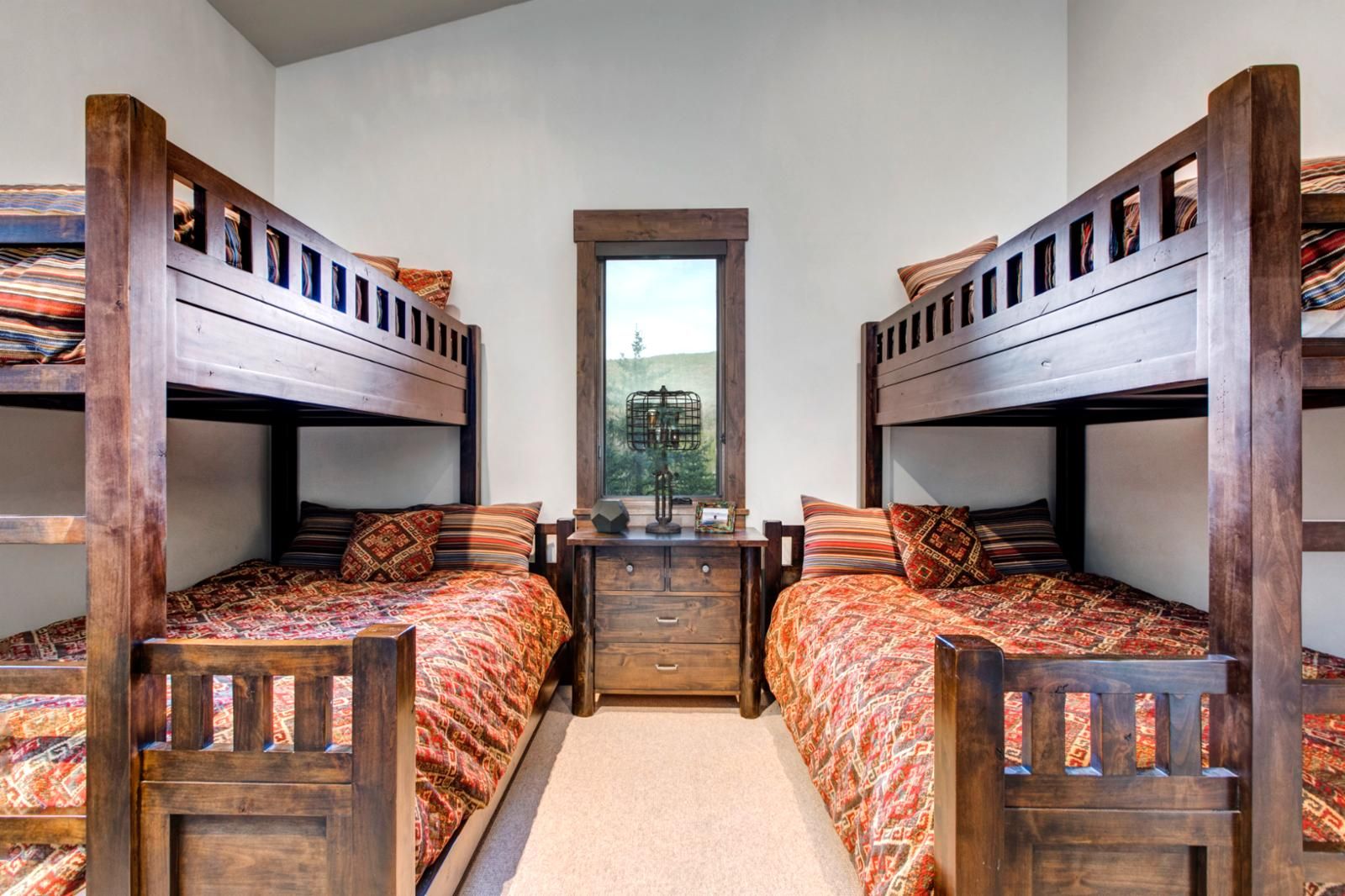 Une chambre avec deux lits superposés, une commode en bois et une fenêtre donnant sur un paysage agréable.