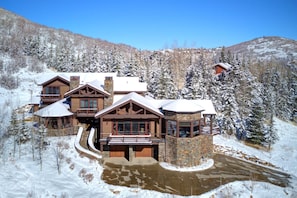 Un gran edificio de estilo lodge con varias habitaciones, una torre de piedra y un paisaje cubierto de nieve.