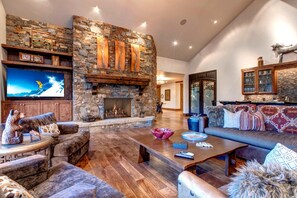 Una sala de estar acogedora con chimenea de piedra, asientos cómodos y un televisor de pantalla plana.
