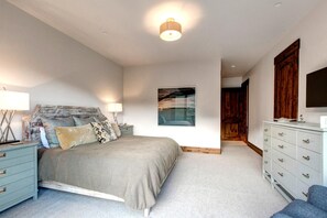 Une chambre à coucher avec un lit, des tables de chevet, une commode et un tableau au mur.