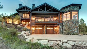 A large, multi-story house with a stone facade, multiple windows, and a balcony.
