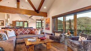 A spacious living room with a large sofa, a coffee table, and a balcony with outdoor seating.