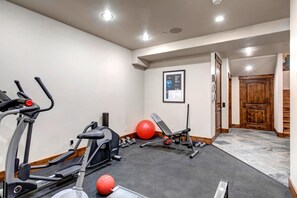 Un gimnasio en casa con equipo de ejercicio, incluyendo cintas de correr, una banca y pesas.
