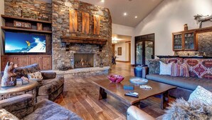 A cozy living room with a stone fireplace, comfortable seating, and a flat-screen TV.