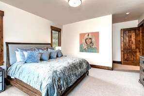 Une chambre à coucher avec un grand lit, une porte en bois et un tableau accroché au mur.