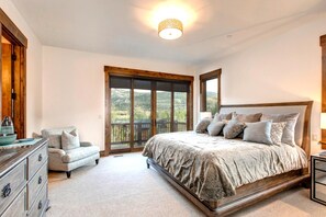 Un dormitorio con una cama grande, un aparador, una silla y vistas al exterior por una puerta corrediza.
