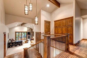 Un intérieur spacieux agrémenté d’un escalier en bois, d’une cheminée en pierre et d’une grande armoire en bois.