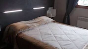 A hotel room with a bed, a bedside table, and a window with curtains.