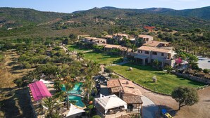Una villa de estilo mediterráneo con piscina, rodeada de exuberante vegetación y colinas.