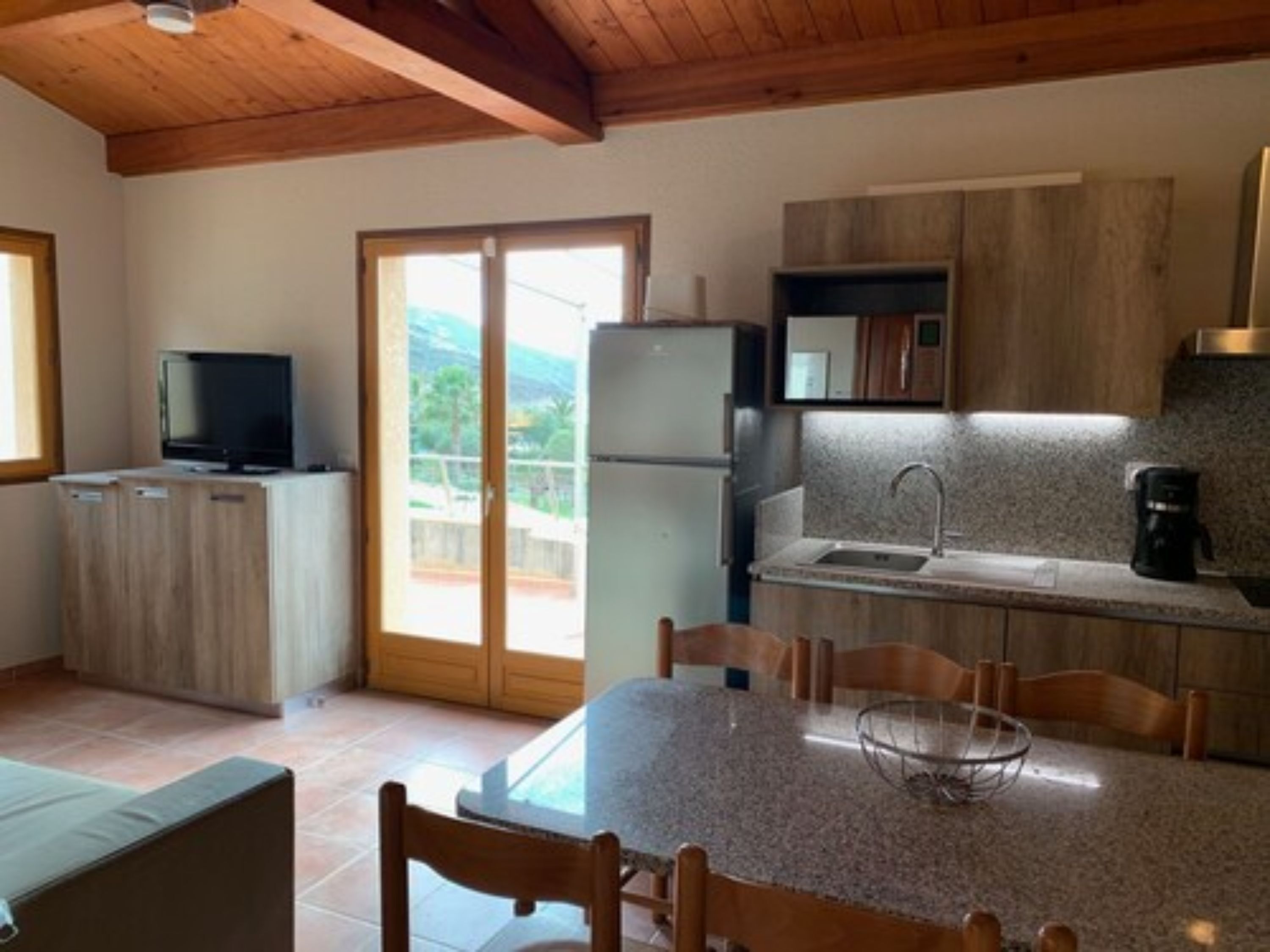 Eine Küche mit Esstisch, Stühlen, Kühlschrank, Spüle und Fernseher.
