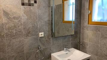 Un baño con un lavamanos blanco, un espejo y un tozaletas.