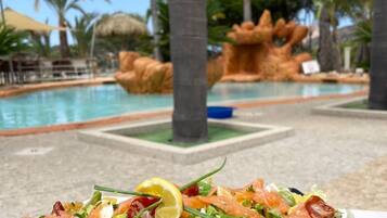 A poolside view with a dining table and a salad in the foreground.