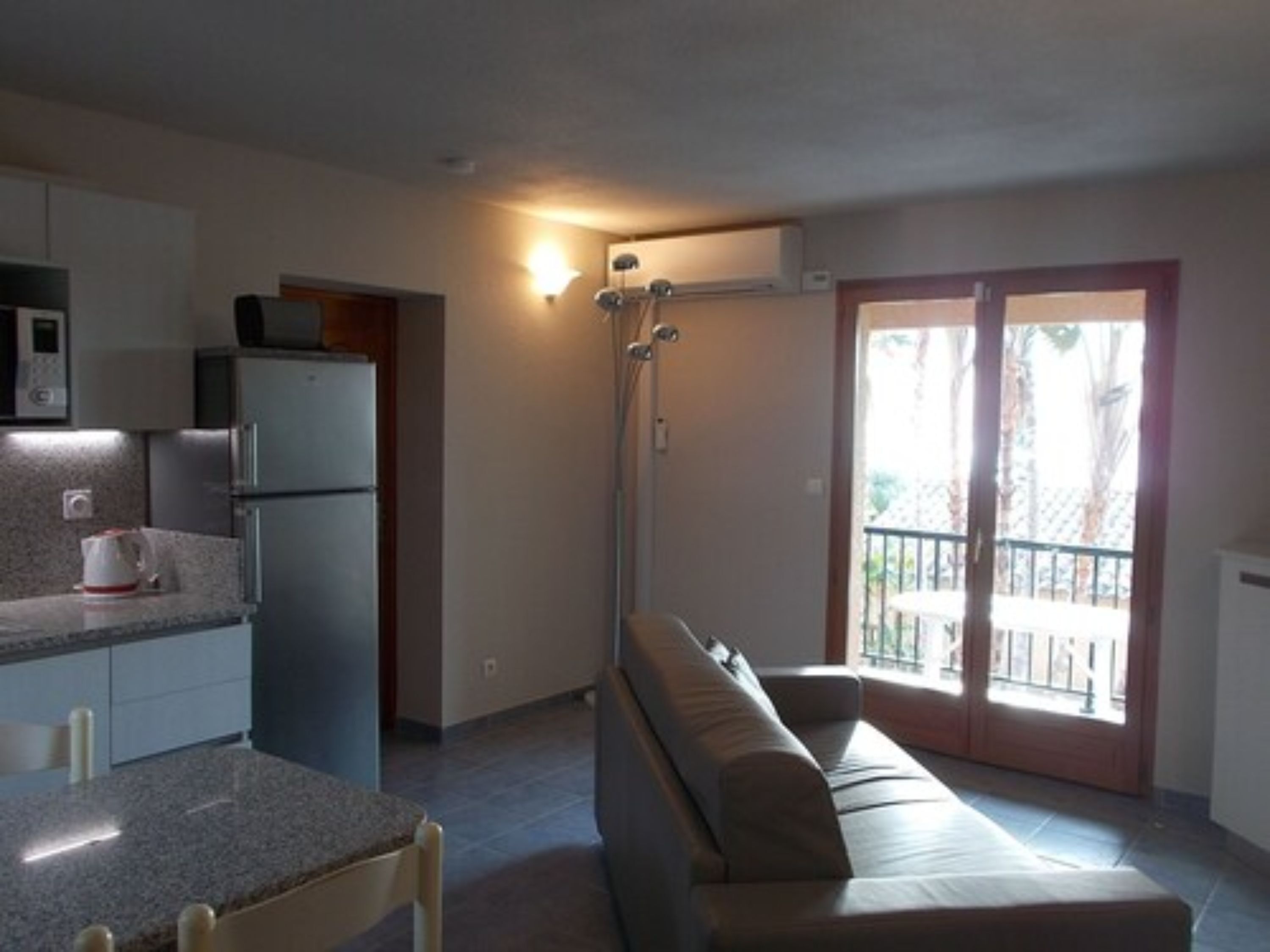 A compact living space with a kitchenette, a sofa, and a balcony.