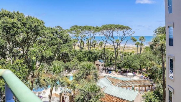 A resort with a pool, palm trees, and a view of the beach.