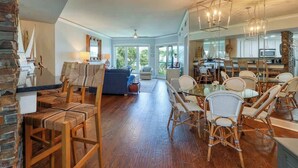 A spacious living area with a dining table and chairs, a sofa, and a kitchen in the background.