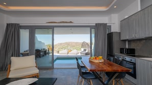 A modern kitchen with a view of the mountains, a dining area with a pool, and a cozy seating area. - Mykonos Village (Mykonos)