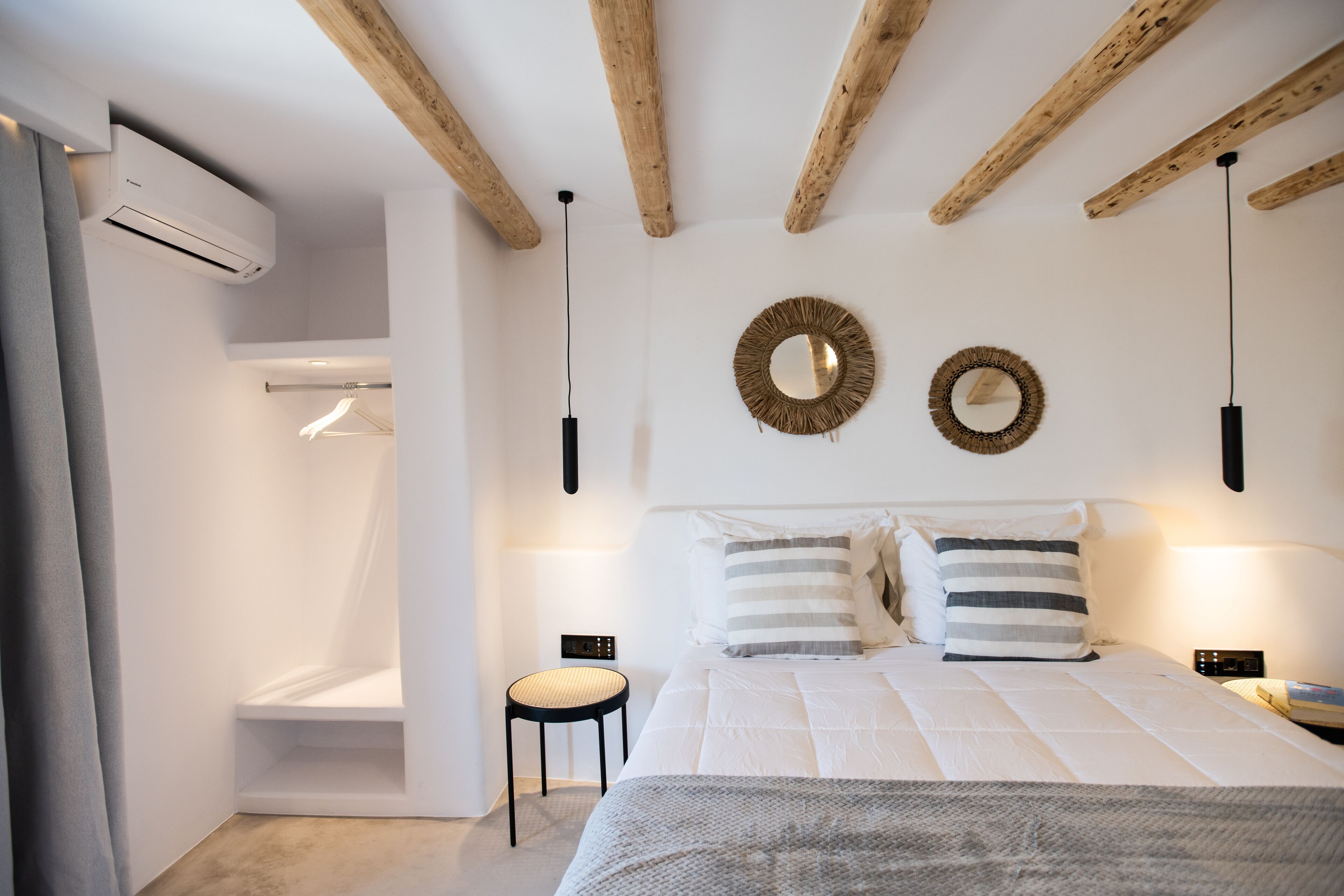 A modern bedroom with a bed, two wall-mounted lights, a wooden ceiling, and a small bedside table.