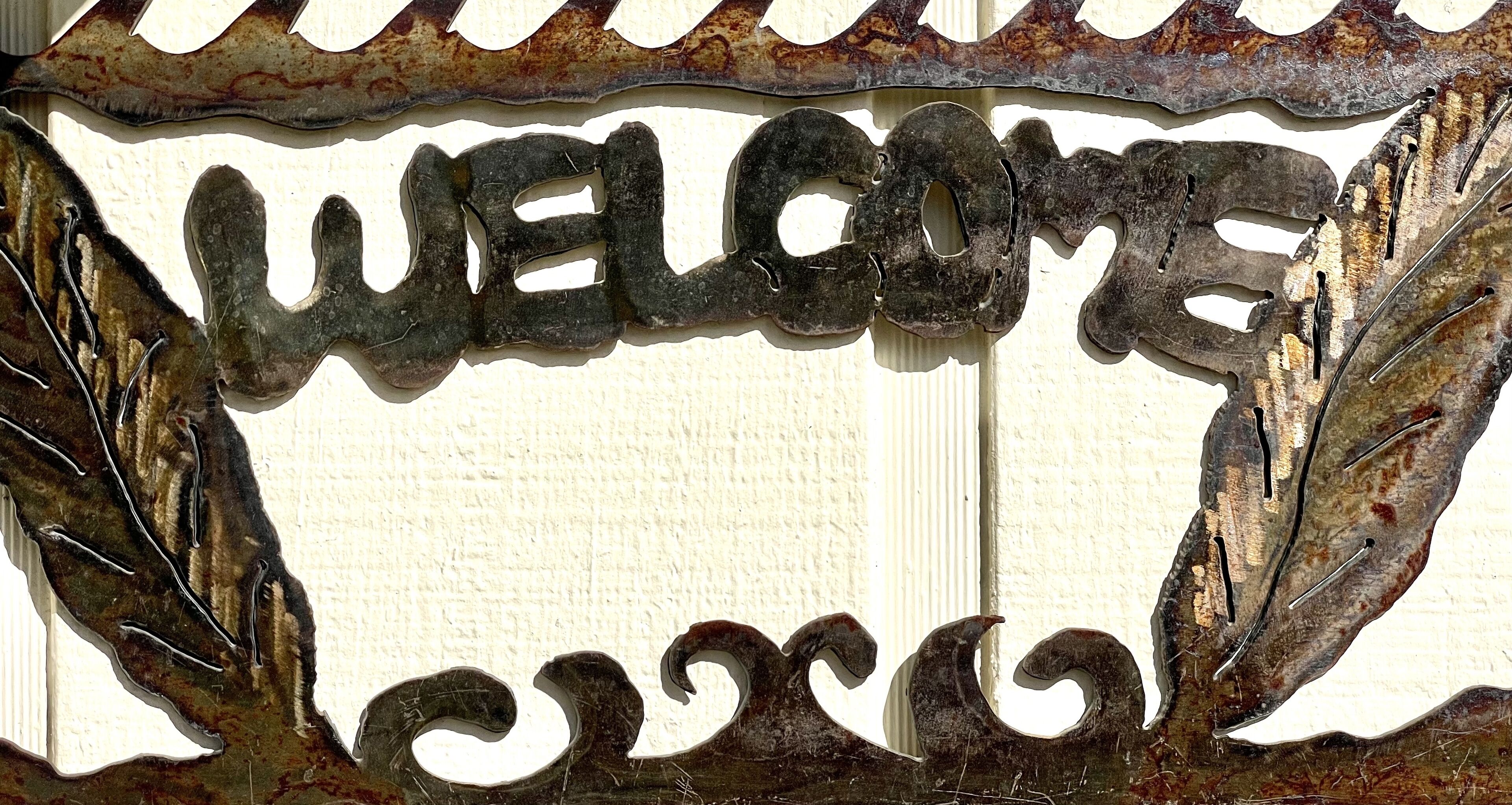 A weathered metal sign with the word "WELCOME" in a decorative font.
