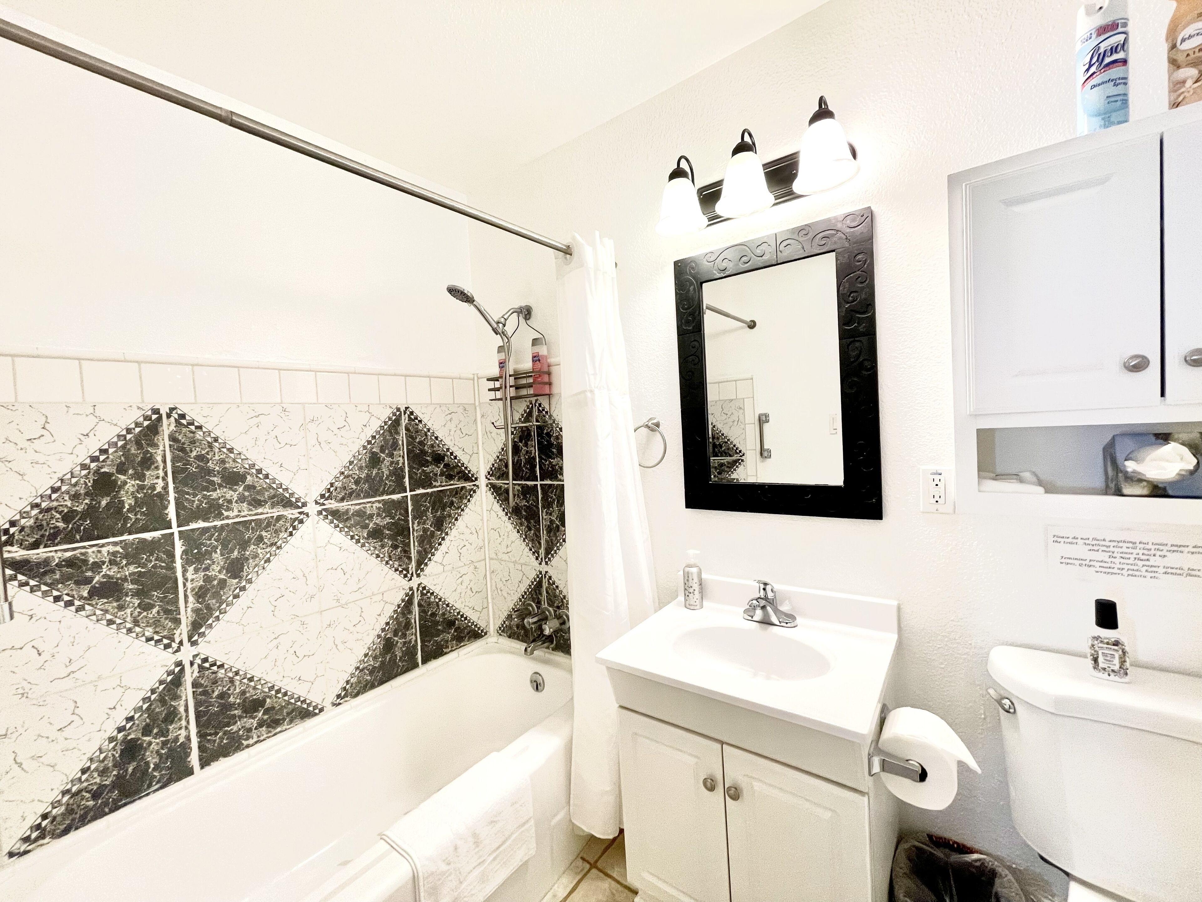A bathroom with a bathtub, a sink, a toilet, a mirror, and a shower curtain.