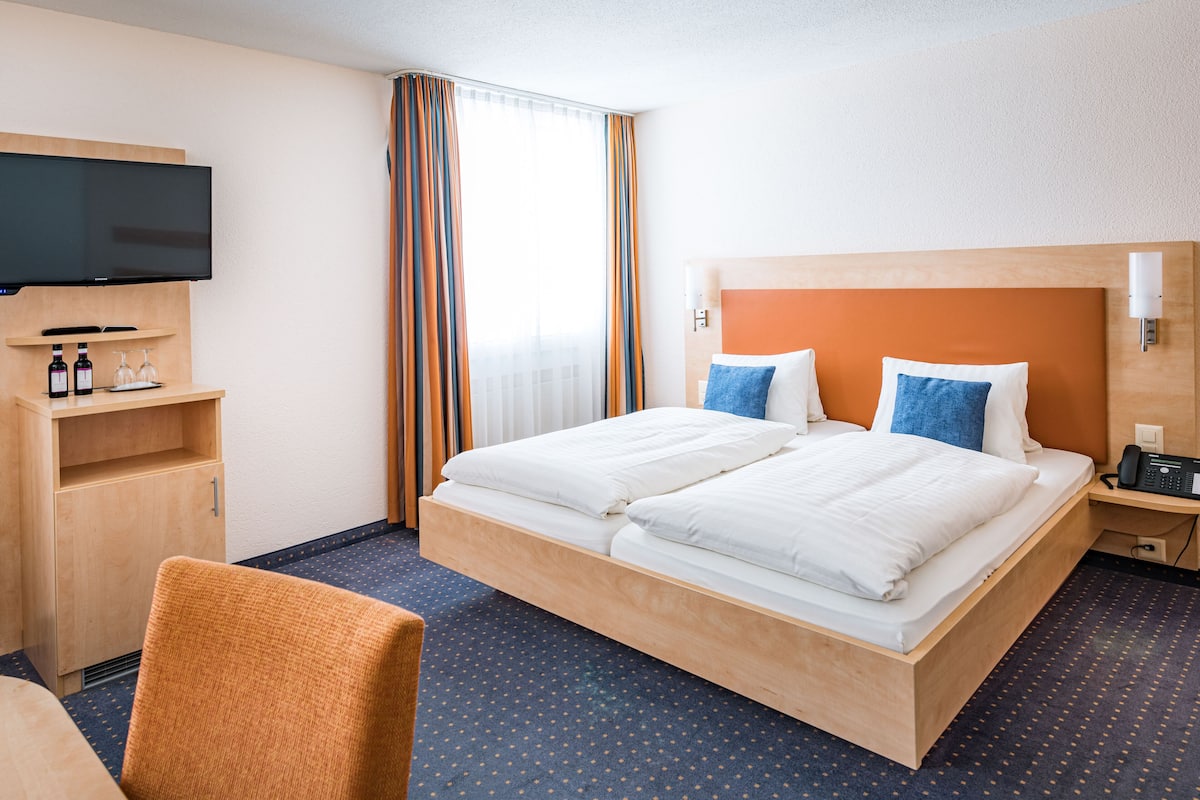 Habitación de hotel con cama, televisión, escritorio y silla.