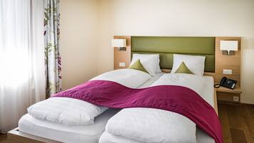 A hotel room with a bed, two bedside lamps, a telephone, and a curtain with a leaf pattern.