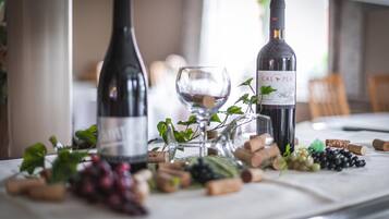 Two wine bottles, a glass, and various corks and grapes on a table.