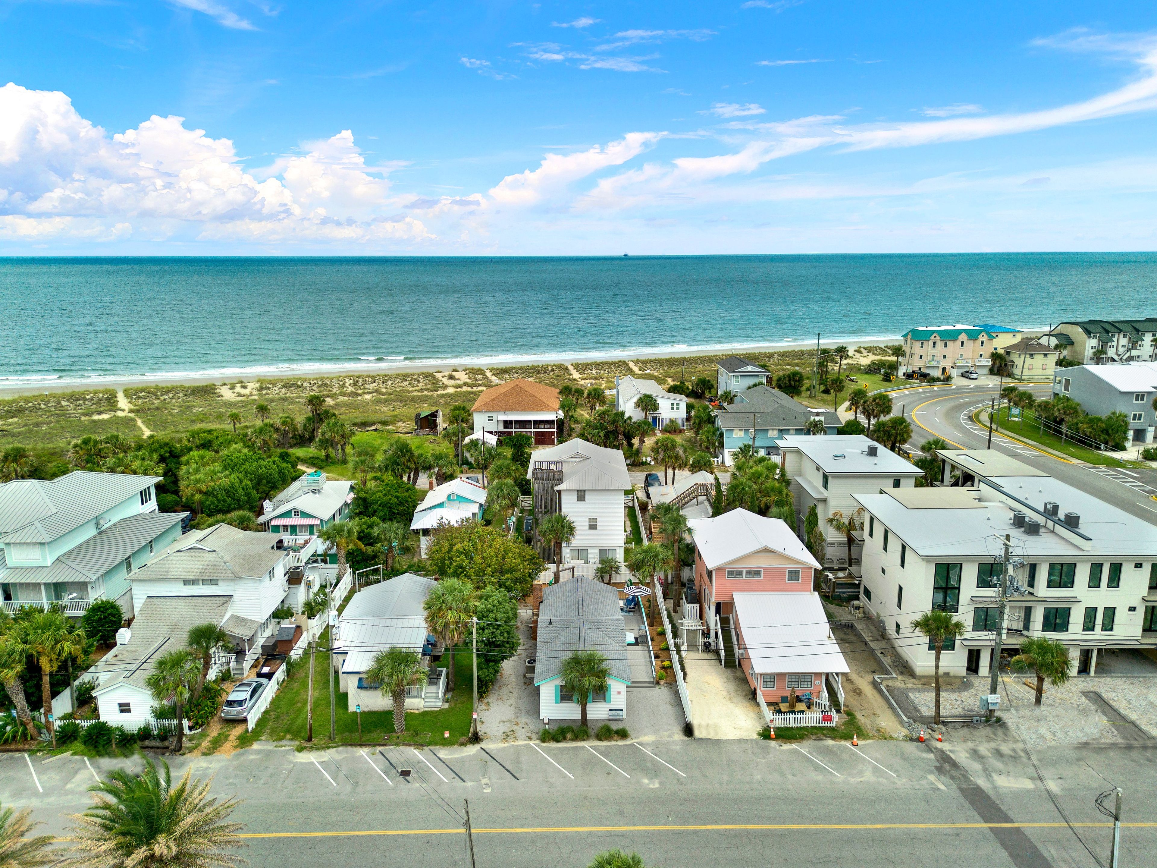 A coastal residential area with houses, a beach, and a clear sky.