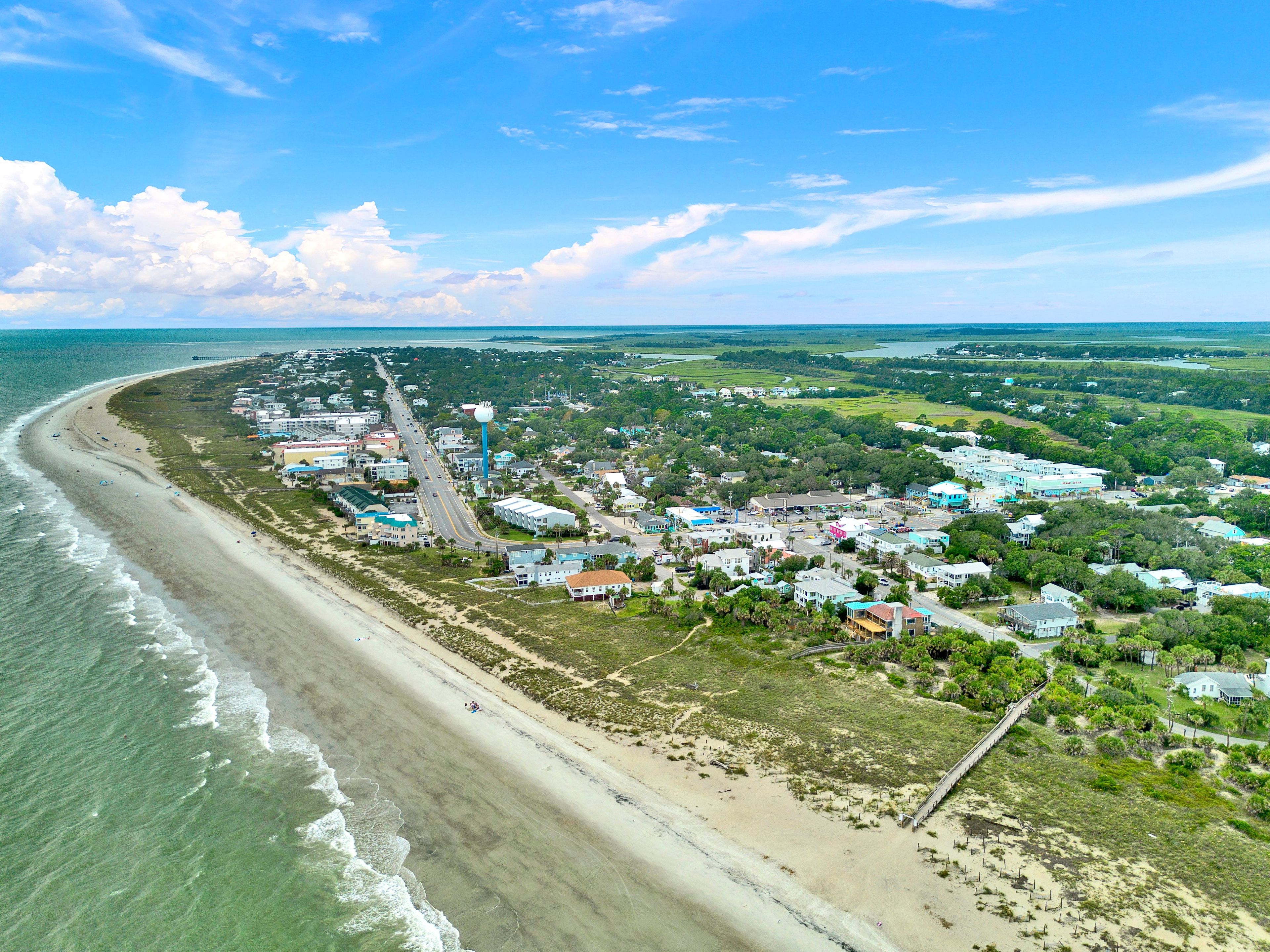 Une vue aérienne d’une ville côtière avec une plage, des maisons et une route.