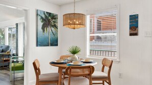 Un coin repas comprenant une table ronde, quatre chaises, un luminaire suspendu et des œuvres d’art accrochées aux murs.