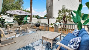 Une terrasse extérieure équipée d’un barbecue, de meubles de jardin et d’un grand parasol.