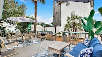 An outdoor deck with a barbecue grill, patio furniture, and a large umbrella.
