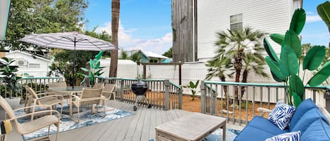 Una terraza exterior con una parrilla, muebles de patio y un gran paraguas.