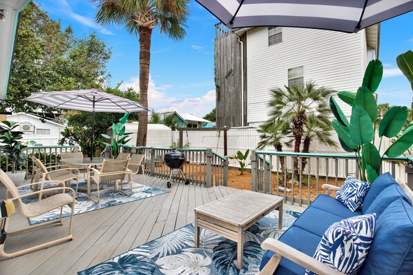 An outdoor deck with a barbecue grill, patio furniture, and a large umbrella.
