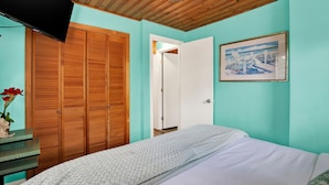 Une chambre à coucher avec un lit, une armoire en bois, une porte et un tableau encadré au mur.