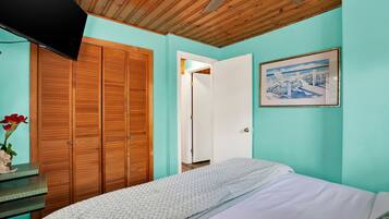 A bedroom with a bed, a wooden wardrobe, a door, and a framed picture on the wall.
