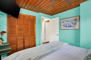 Una camera da letto con un letto, un armadio in legno, una porta e un quadro appeso al muro.