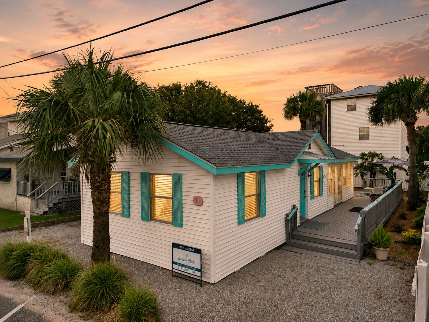 A small, single-story building with a sloped roof, a porch, and a sign indicating pool access.