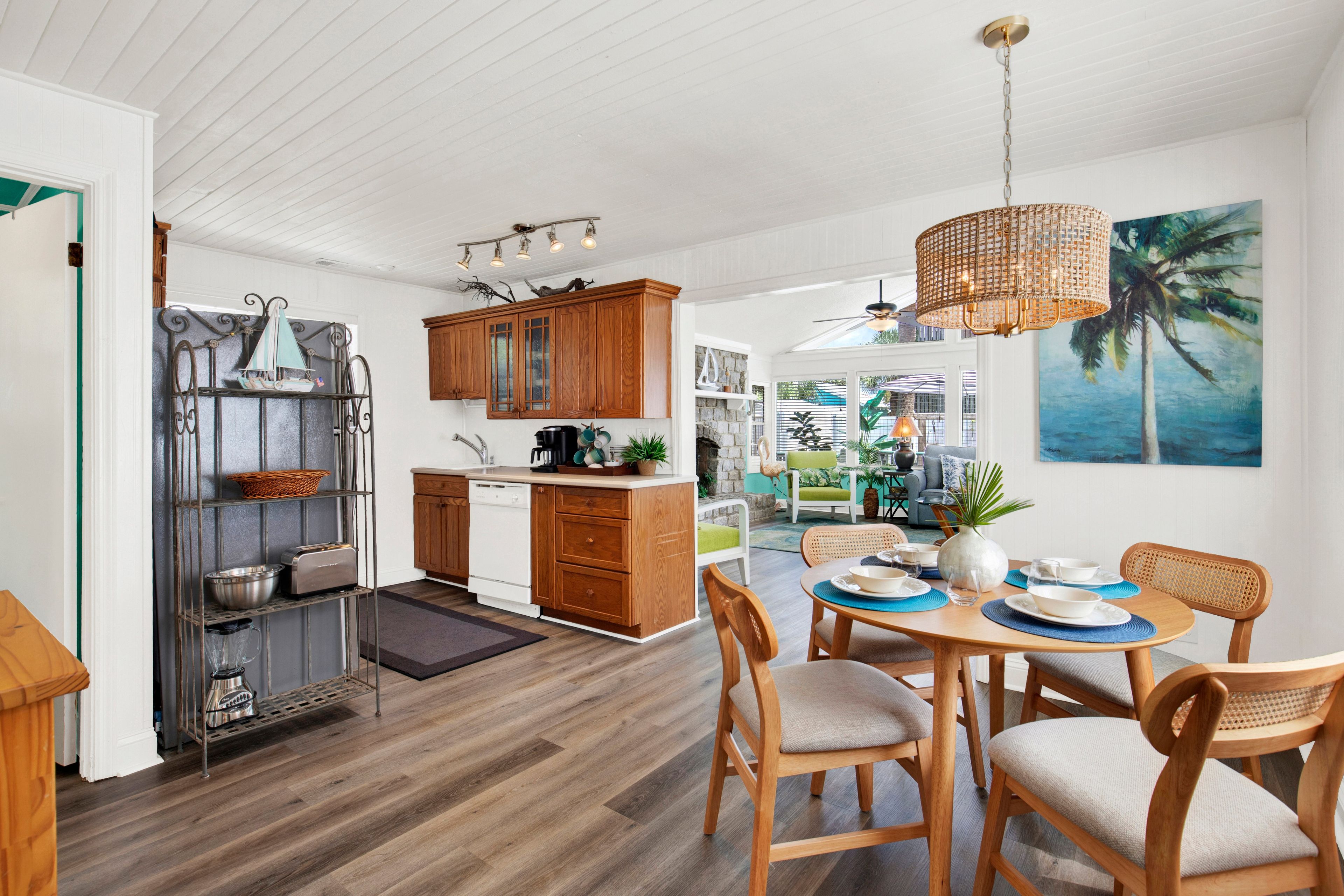 A modern kitchen with wooden cabinets, a dining area with a table set for two, and a view of the outdoors.