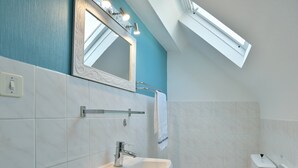 Un baño moderno con tragaluz, un lavabo blanco y un inodoro.