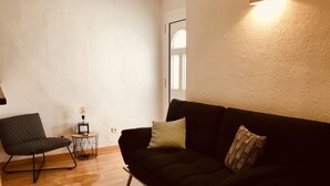 Een woonkamer met een zwarte bank, een ronde salontafel en een moderne fauteuil.
