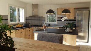 Una cocina moderna con armarios de madera, encimera negra y refrigerador de acero inoxidable.