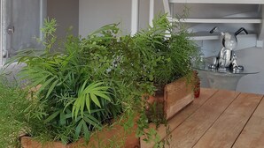 Una mesa de madera con un jardinero de plantas verdes, dos lámparas colgantes y una escalera con una viga de madera.