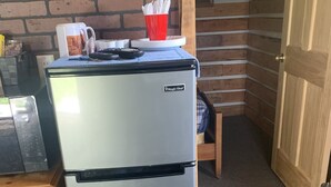 Cocina compacta con refrigerador de acero inoxidable, un armario de madera y pared de ladrillo.