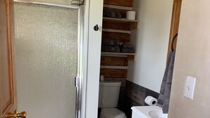 Un baño pequeño con ducha, inodoro y lavamanos.