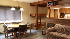 A cozy living room with a wooden dining table, two chairs, a patterned sofa, and a small table with a plant. - MOOSE-WILSON ROAD- WILSON, WY- PERFECT LOCATION AND GREAT FAMILY RETREAT! (Wilson)
