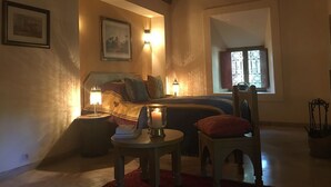 Una habitación acogedora con una cama, una mesita con una vela y una silla.