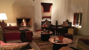 Una sala acogedora con chimenea, cojines estampados y una alfombra tradicional.