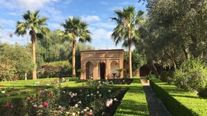 Un jardín con un edificio central, rodeado de setos cuidados y plantas en flor.