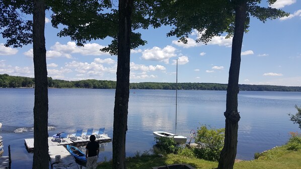 A lakeside view with a dock, a boat, and a person standing by the water. - Lakefront  Retreat on Galway Lake, NY (Galway)